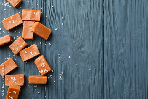 Salted caramel candies on wooden background, space for text
