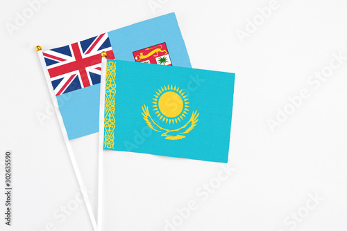Kazakhstan and Fiji stick flags on white background. High quality fabric, miniature national flag. Peaceful global concept.White floor for copy space.