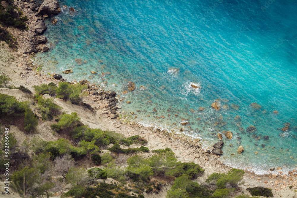 ibizTop view of a rocky beach from the top birds view turquoise sea water green plants vegetation Mediterranean beach on Ibiza island near Cala D'Hort a
