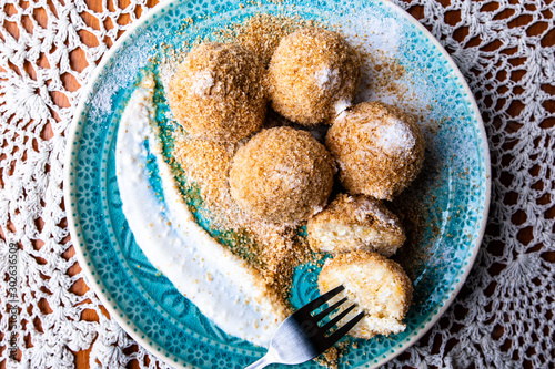 Cottage cheese dumplings with breadcrumbs and powdered sugar on a decorative plate