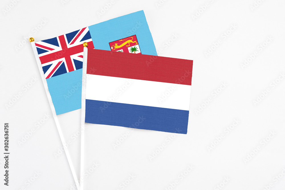Netherlands and Fiji stick flags on white background. High quality fabric, miniature national flag. Peaceful global concept.White floor for copy space. Netherlands and Fiji stick flags on white background. High quality fabric, miniature national flag. Peaceful global concept.White floor for copy space.