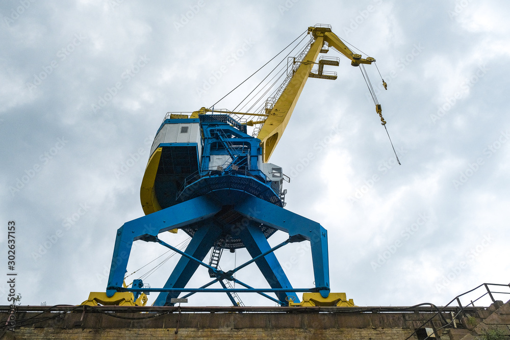 the gantry crane working at the seaport against the clouds the gantry crane working at the seaport against the clouds