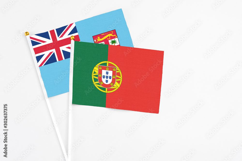 Fototapeta premium Portugal and Fiji stick flags on white background. High quality fabric, miniature national flag. Peaceful global concept.White floor for copy space.
