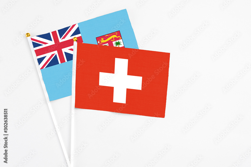 Switzerland and Fiji stick flags on white background. High quality fabric, miniature national flag. Peaceful global concept.White floor for copy space.