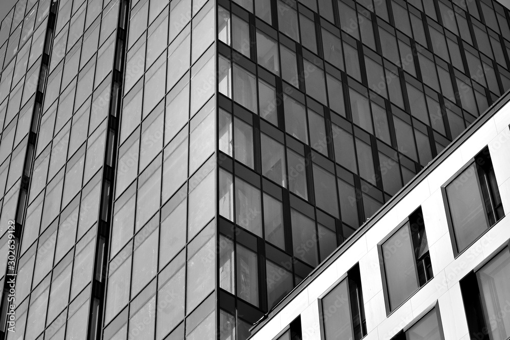 Curtain wall made of toned glass and steel constructions under sky. A fragment of a building. Black and white. Curtain wall made of toned glass and steel constructions under sky. A fragment of a building. Black and white.