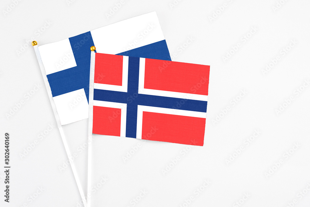 Bouvet Islands and Finland stick flags on white background. High quality fabric, miniature national flag. Peaceful global concept.White floor for copy space.