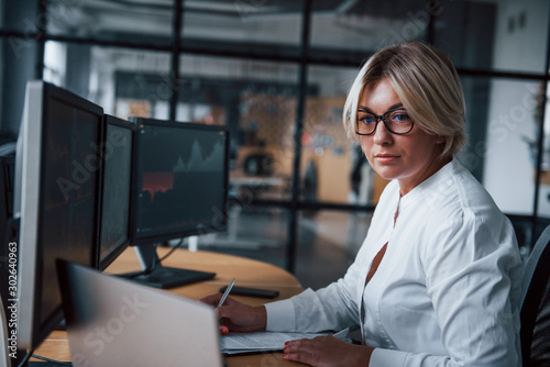 Female stockbroker in formal clothes works in the office with financial market