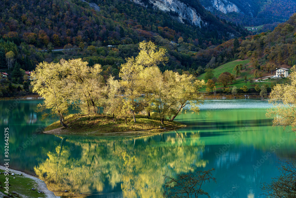 Close-up of a small island in a beautiful Alpine lake in autumn. Lago di Tenno, Trento province, Trentino-Alto Adige, Italy, Europe