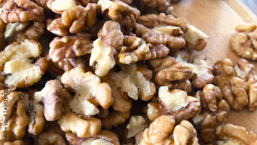 Movement in a circle of a group of peeled walnuts. Walnut rotates on a turntable and pours from above. Top view, close-up. Movement in a circle of a group of peeled walnuts. Walnut rotates on a turntable and pours from above. Top view, close-up.