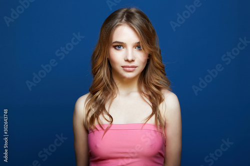 Beautiful young woman in pink dress over blue background