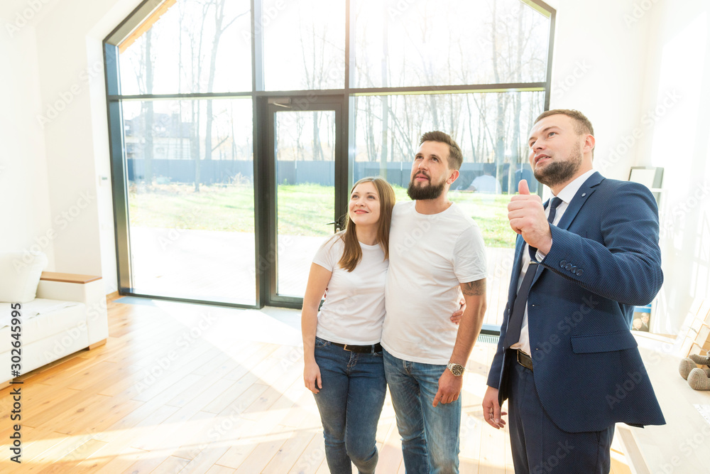 real estate agent shows a young couple a new home. family buys housing real estate agent shows a young couple a new home. family buys housing