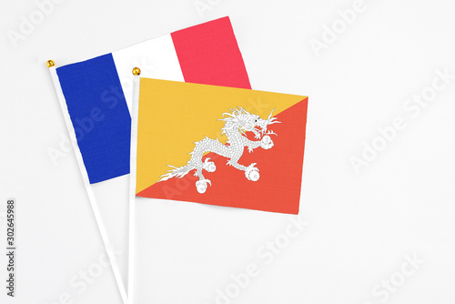 Bhutan and France stick flags on white background. High quality fabric, miniature national flag. Peaceful global concept.White floor for copy space.