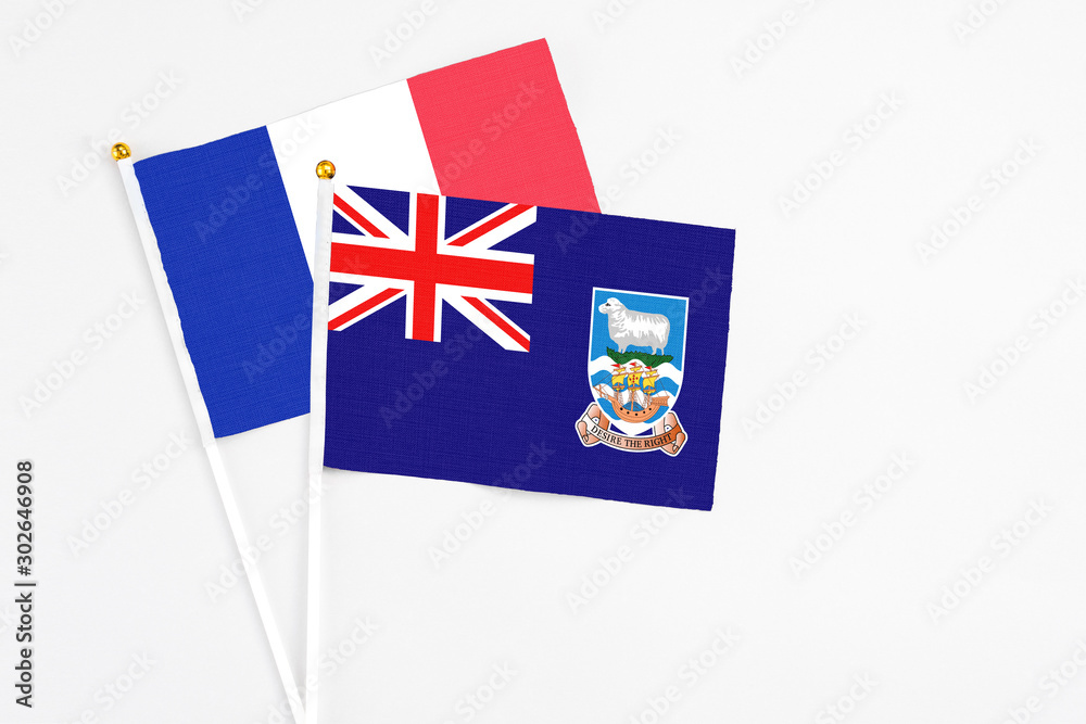 Fototapeta premium Falkland Islands and France stick flags on white background. High quality fabric, miniature national flag. Peaceful global concept.White floor for copy space.