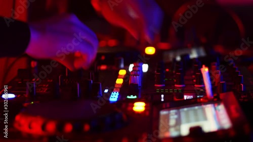 Close-up of DJ hands working on the remote control at night club