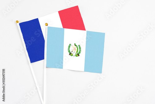 Guatemala and France stick flags on white background. High quality fabric, miniature national flag. Peaceful global concept.White floor for copy space.