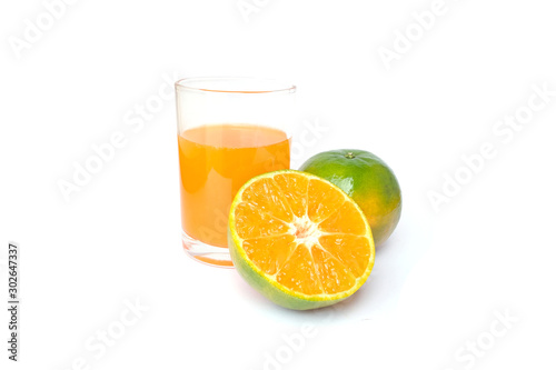 100  of fresh Orange juice in glass with Green oranges and sliced i