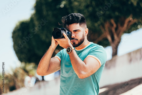 Young man with DSLR camera in city