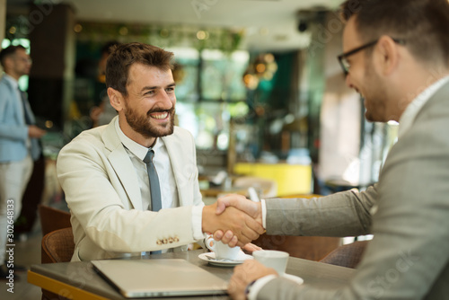 Businessmen shaking hands after meeting in a cafe