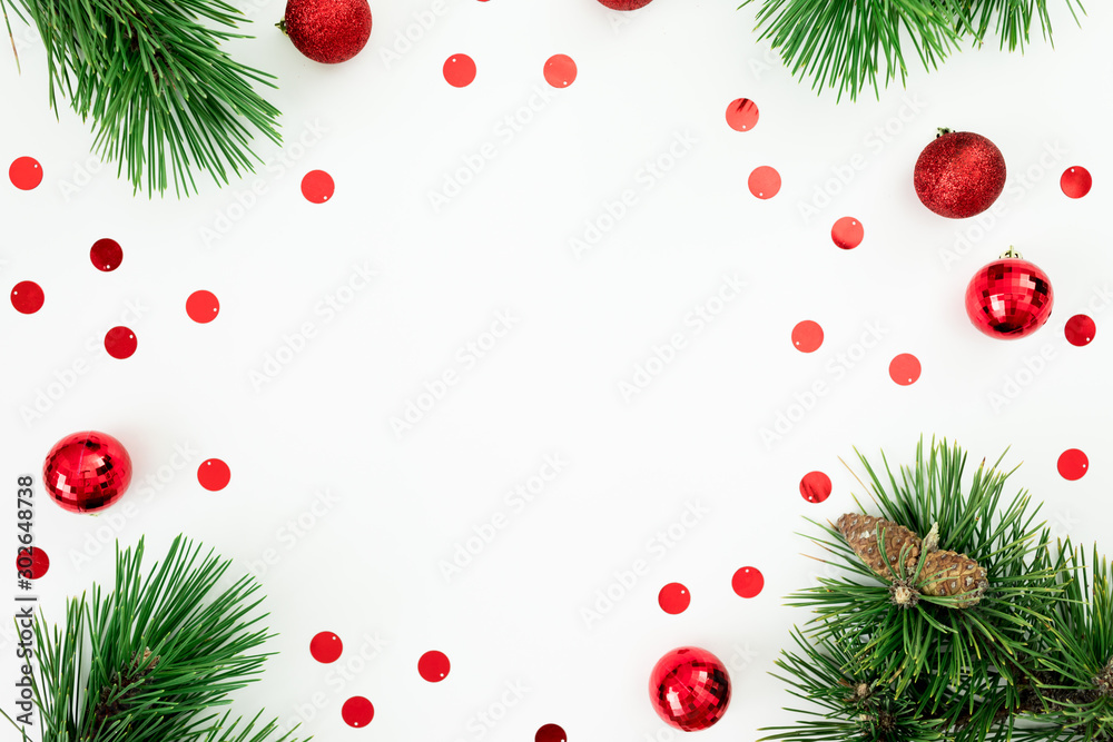Christmas frame made of pine branches and red balls decoration with confetti on white background. Flat lay Christmas frame made of pine branches and red balls decoration with confetti on white background. Flat lay