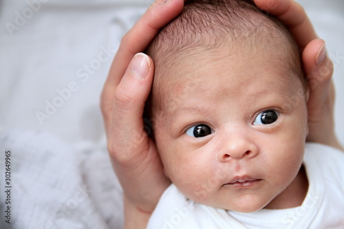 baby wrapped up in blanket looking with big blue eyes just been cared for after having a good sleep in bed with mother stock photograph stock photo