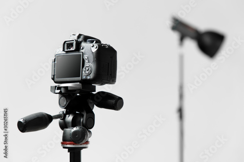 Photo camera on the tripod. Studio shot on gray background