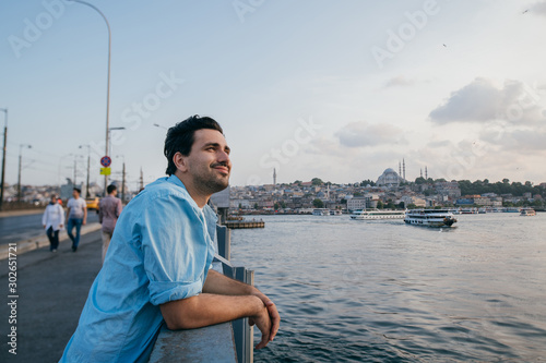 A young man on the bridge looks into the distance on the city.