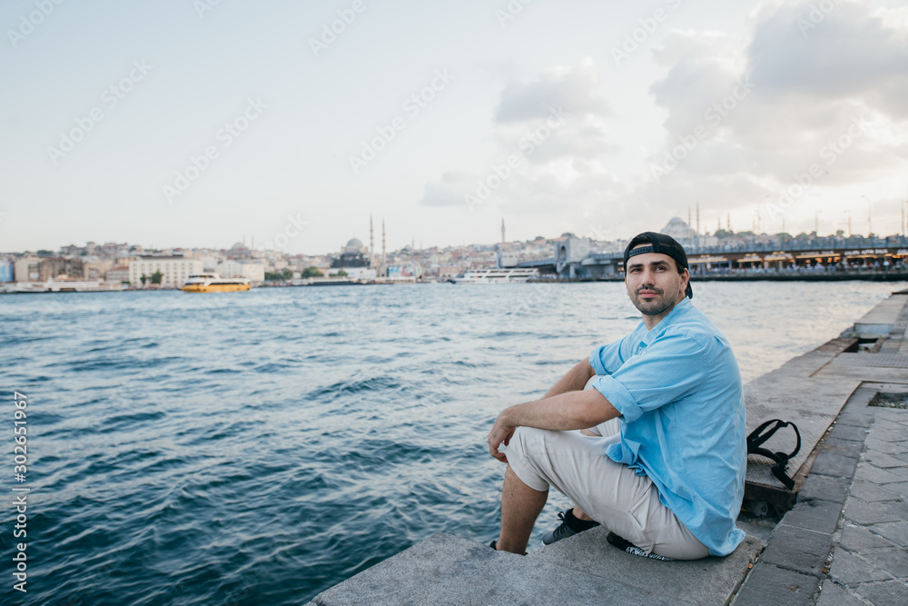 Portrait of a young man against the background of the sea, city, pier and ships. Portrait of a young man against the background of the sea, city, pier and ships.