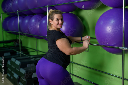 A fat woman is engaged in aerobics and trying to lose weight. An obese girl is relaxing in the gym with fitness balls.
