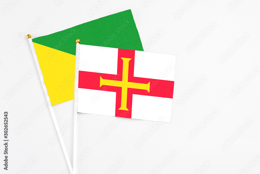 Guernsey and French Guiana stick flags on white background. High quality fabric, miniature national flag. Peaceful global concept.White floor for copy space.