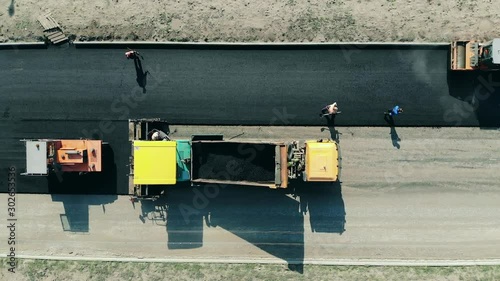 Roadway is getting made from bitum by the workers. Asphalt paver machine on a road construction site. photo