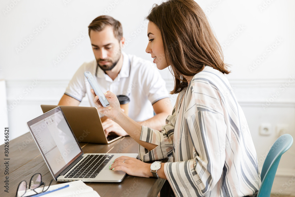 Pleased couple colleagues work with laptops Pleased couple colleagues work with laptops