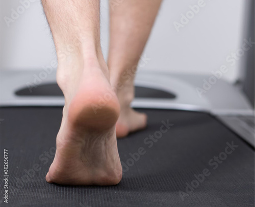 Pies de hombre descalzos andando sobre cinta de correr