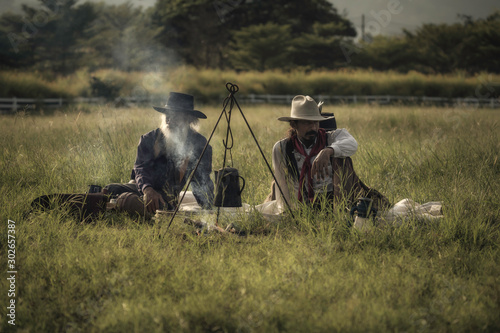 The Cowboys sitting on the camp in the evening on the meadow While boiling water