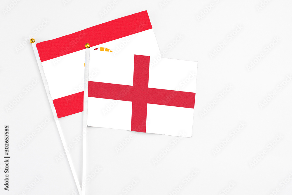 England and French Polynesia stick flags on white background. High quality fabric, miniature national flag. Peaceful global concept.White floor for copy space.