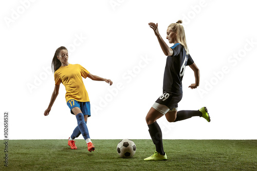 Young female soccer or football players with long hair in sportwear and boots training on white background. Concept of healthy lifestyle, professional sport, motion, movement. Fight for goal. © master1305