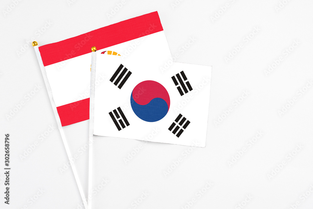 South Korea and French Polynesia stick flags on white background. High quality fabric, miniature national flag. Peaceful global concept.White floor for copy space.