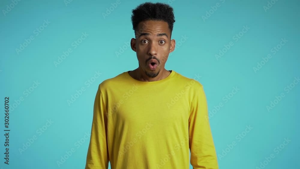 Amazed mixed race man shocked, saying WOW. Handsome african american guy with afro hair surprised to camera over blue background. Amazed mixed race man shocked, saying WOW. Handsome african american guy with afro hair surprised to camera over blue background.