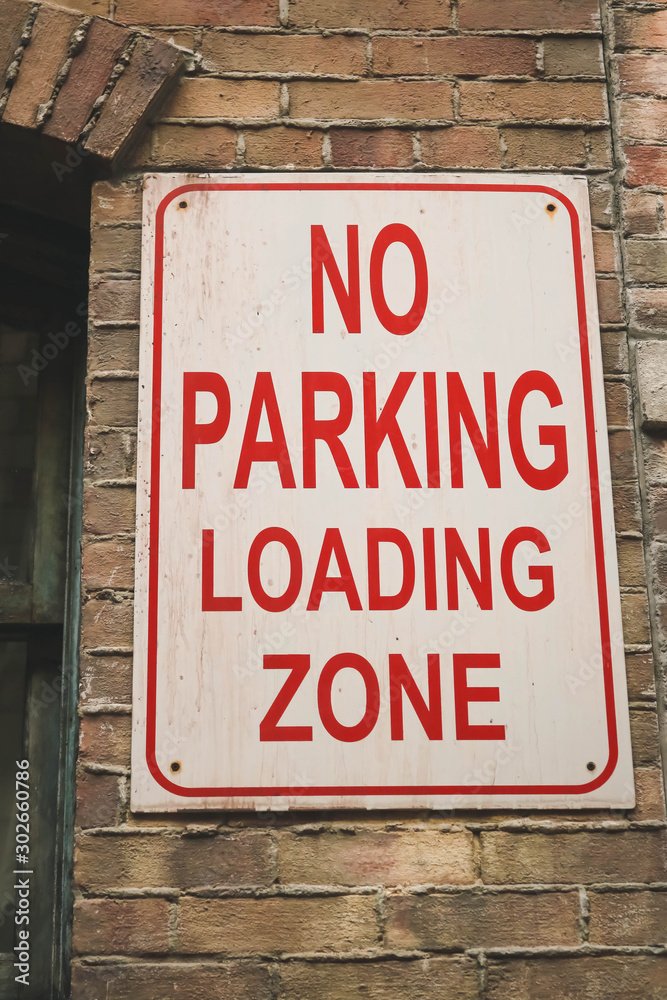 No parking loading zone sign on the brown brick wall. No parking loading zone sign on the brown brick wall.