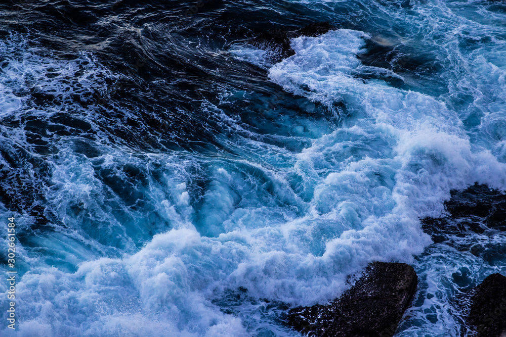 Violent energetic waves crashing on a rock in Sydney Australia. Light and dark blue water foaming whilst waves break to the shore. Deep Sea.