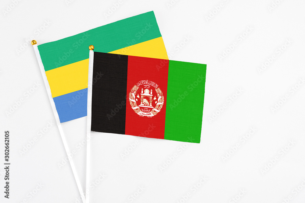 Fototapeta premium Afghanistan and Gabon stick flags on white background. High quality fabric, miniature national flag. Peaceful global concept.White floor for copy space.