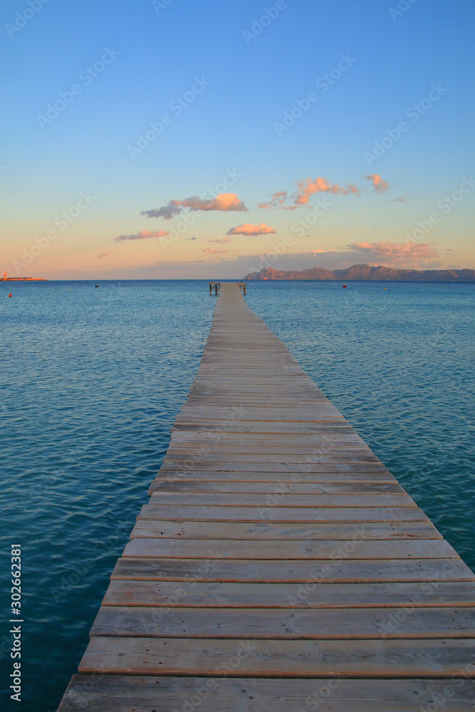 Wooden pier going to sea at sunset.