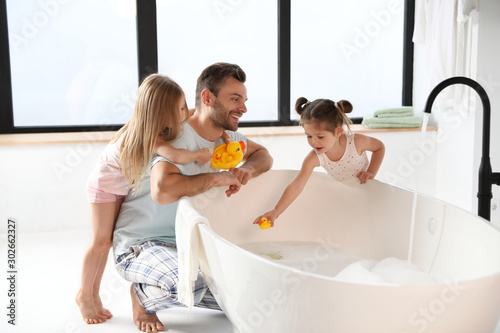 Obraz na płótnie Young father with little daughters in bathroom