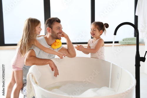 фотографія Young father with little daughters in bathroom