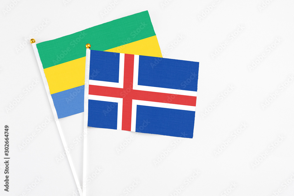 Iceland and Gabon stick flags on white background. High quality fabric, miniature national flag. Peaceful global concept.White floor for copy space.