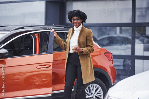 Young african american woman in glasses stands outdoors near modern car © standret