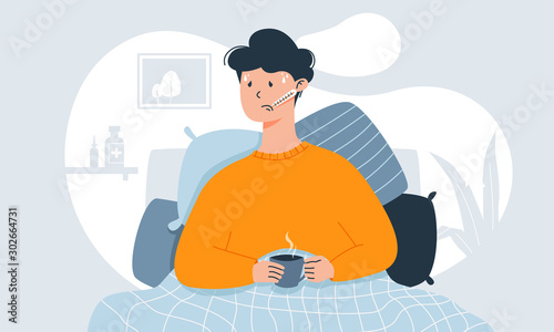 Young man with cold symptoms like fever, headache and sore throat measuring temperature in his bed, holding cup of tea. photo