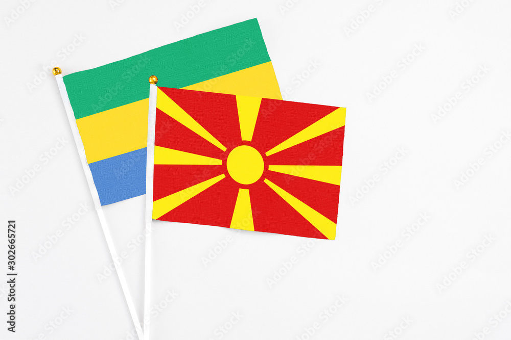 Macedonia and Gabon stick flags on white background. High quality fabric, miniature national flag. Peaceful global concept.White floor for copy space.