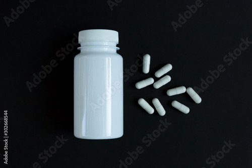 Capsules medication with a jar open in the background