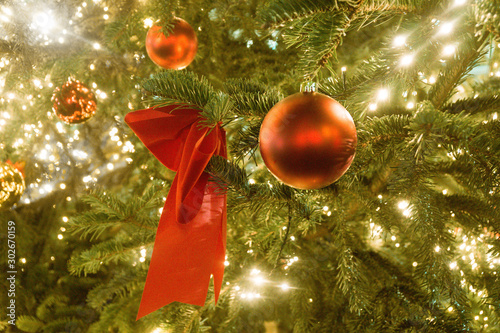 festive red christmas ball and decorative bow on green pine tree branch