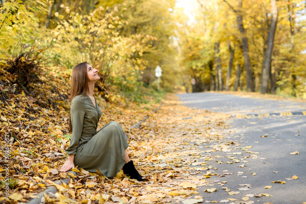 Autumn colours. Beautiful woman in coat posing in forest on roadside